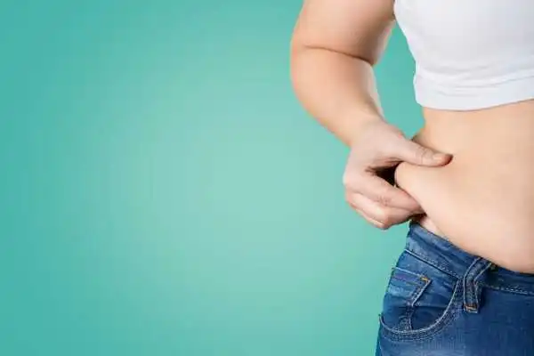 Image of woman pinching her love handles to show weight gain Windlesham